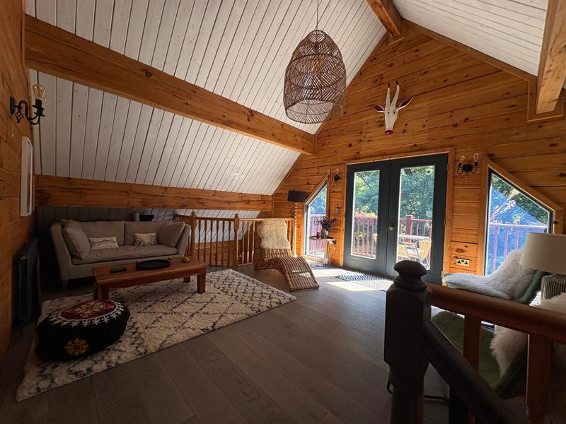 The family room on the top floor, with a sofa, a chaise and doors onto the balcony over the creek